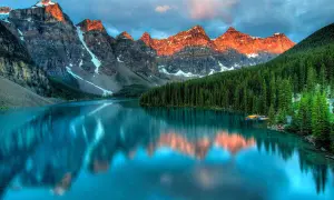 Lago turchese riflette le montagne italiane più famose, con foreste di conifere e cielo nuvoloso.