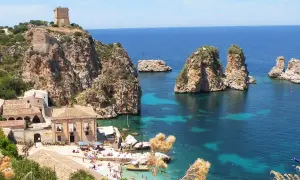 Scogliera con torre a Castellammare del Golfo, mare cristallino e faraglioni.