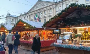 Mercatini di Natale Aosta: bancarelle addobbate con luci e ghirlande, prodotti tipici e gente che passeggia. Atmosfera magica.