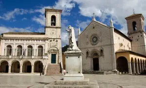 La piazza di Norcia con la basilica e il palazzo comunale, dominata dalla statua di San Benedetto. La basilica di Norcia oggi si presenta maestosa.