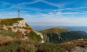 Croce metallica su un crinale roccioso, con vista panoramica sulle colline verdi dell'Emilia Romagna. Perfetto per escursioni.