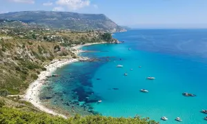 Spiaggia dorata, acque cristalline e barche all'orizzonte: ecco cosa fare in Calabria per una vacanza indimenticabile.