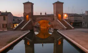 Ponte di barche a Comacchio, uno dei borghi medievali vicino a Ferrara, con le sue torri illuminate e il riflesso sull'acqua.