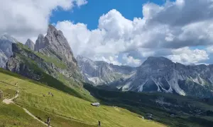 Sentiero panoramico tra prati verdi e vette maestose, ideale per escursioni in Alto Adige.