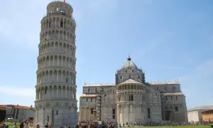 La Torre di Pisa si può salire, con la cattedrale sullo sfondo. Turisti ammirano la celebre struttura pendente sotto un cielo azzurro.