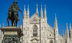 Statua equestre davanti al maestoso Duomo di Milano, con le sue guglie che svettano verso il cielo azzurro.