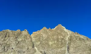 Cime rocciose del Monviso, con la via normale che sale verso la vetta sotto un cielo azzurro intenso.