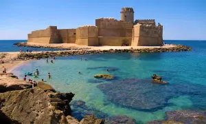 Castello Aragonese su un'isola con mare cristallino, bagnanti e rocce. Un vero spettacolo del **calabria mare bello**.