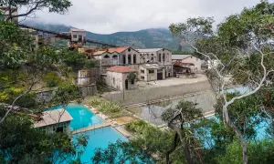 Antica zona mineraria sarda con edifici abbandonati e vasche d'acqua turchese.