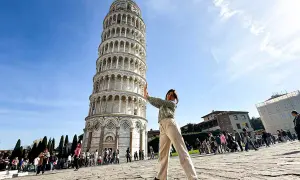 Ragazza fa finta di sorreggere la torre di Pisa, icona mondiale.