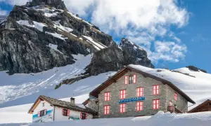 Rifugio Gabiet, uno dei rifugi valle d'Aosta facili, immerso nella neve con montagne imponenti sullo sfondo.