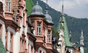 Edifici storici con torrette e tetti verdi, un assaggio di cosa vedere a Bolzano in un giorno, con montagne sullo sfondo.