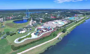 Mirabilandia, un parco acquatico con scivoli colorati e piscine, si trova vicino a un lago, con una ruota panoramica sullo sfondo.