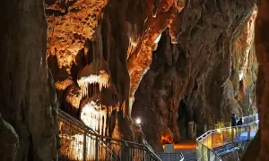 Sentiero illuminato tra le stalattiti delle grotte di Pastena, con persone che passeggiano.