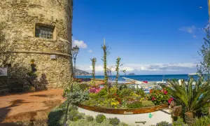Laigueglia centro storico: torre medievale, barca fiorita e mare blu.