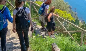 Gruppo di escursionisti sul sentiero degli dei ad Agerola, con vista sul mare blu e vegetazione mediterranea.