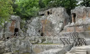 Antiche tombe etrusche scavate nella roccia, con sentieri e recinzioni in legno. Un suggestivo scorcio della mappa dei siti etruschi in Toscana.