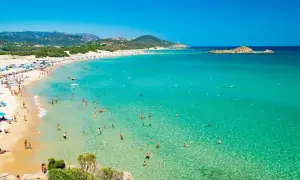 La spiaggia più bella della Sardegna, con sabbia dorata, acque cristalline e tante persone che si godono il sole e il mare.