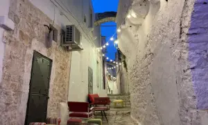 Un vicolo suggestivo con luci soffuse, sedute colorate e un arco in pietra. Perfetto per scoprire cosa vedere vicino Alberobello.