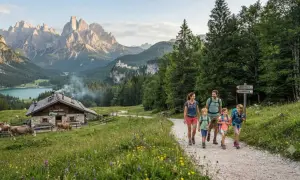 Famiglia in escursione in Trentino, con un rifugio alpino, mucche al pascolo e montagne maestose sullo sfondo.