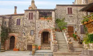 Un angolo di uno dei **borghi più belli della Toscana**, con case in pietra, scale in cotto e piante rigogliose.