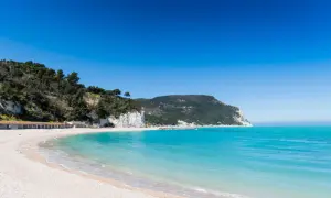 Spiagge di San Benedetto del Tronto con scogliere bianche, vegetazione lussureggiante e mare cristallino sotto un cielo azzurro.