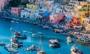 Colorate case a picco sul mare blu, con barche ormeggiate. Un luogo perfetto per escursioni da Napoli.