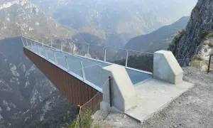 La passerella panoramica "Becco di Dossena" si protende su un profondo canyon, offrendo una vista mozzafiato sulle montagne circostanti.