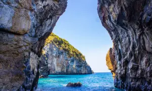 Vista da una grotta su un mare cristallino e una scogliera verdeggiante. Un vero paradiso, tra le scalea spiagge più belle.