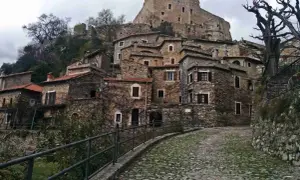 Antico borgo di Castelvecchio di Rocca Barbena, con case in pietra e un castello in cima alla collina.