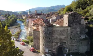 Antica porta in pietra lungo la via del Volto Santo, con fiume e case arroccate sui monti.