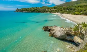 Spiaggia dorata e mare cristallino nel Cilento, uno dei posti più belli del Cilento mare, con una torre antica a picco sul blu.
