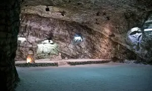 Interno della cattedrale di sale di Realmonte, con pareti rocciose stratificate e un altare illuminato.
