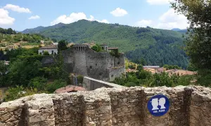 Rovine di un castello a Castiglione di Garfagnana, con un cartello "Kiss... Please" su un muretto di pietra.
