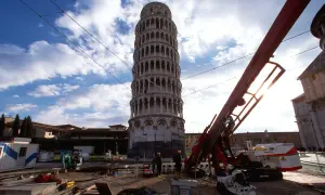La Torre di Pisa prima e dopo i lavori di consolidamento: un cantiere con macchinari e operai accanto alla torre pendente.