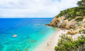 Spiaggia incantevole con acque cristalline, rocce dorate e vegetazione lussureggiante. Un angolo di paradiso, quasi un mare vicino Firenze, dove rilassarsi.