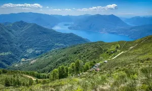 Panoramica mozzafiato di un lago alpino e montagne verdi, ideale per passeggiate vicino Milano.