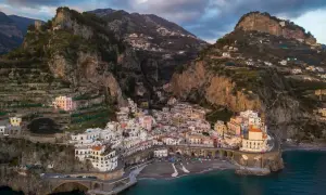 Un borgo pittoresco sulla Costiera Amalfitana, tra i paesi più belli d'Italia, aggrappato alla roccia con case colorate e mare blu.