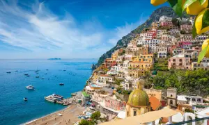 Positano, un gioiello da scoprire tra le cose da visitare in Campania. Case colorate a picco sul mare blu, barche e una spiaggia vivace.