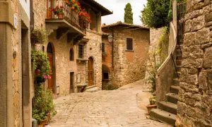 Un vicolo acciottolato tra antichi borghi toscani poco conosciuti, con case in pietra, balconi fioriti e un'atmosfera senza tempo.