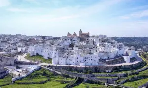 Panoramica di uno dei borghi medievali in Puglia, con case bianche a picco sul mare e un cielo azzurro.