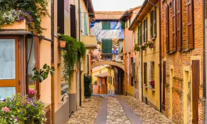 Un vicolo pittoresco tra i borghi medievali dell'Emilia Romagna, con case colorate, fiori e murales vivaci.