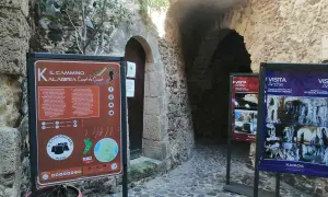 Cartello informativo sul Cammino Calabria Coast to Coast, con scorci di antiche costruzioni in pietra.