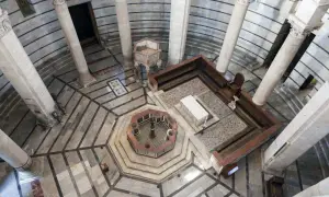 Interno della Torre di Pisa: vista dall'alto del battistero ottagonale, colonne imponenti e mosaici sul pavimento.
