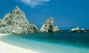 Spiaggia bianca e mare cristallino, rocce imponenti emergono dall'acqua turchese. Un angolo di paradiso nelle Marche, mare bello da cartolina.