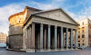 Il Pantheon, una delle chiese particolari di Roma, con il suo portico colonnato e la cupola imponente, si staglia sotto un cielo azzurro.