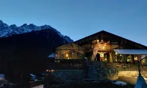 Rifugio alpino illuminato con una stella di Natale, circondato da montagne innevate. I forni di sopra sono spenti, ma l'atmosfera è calda e accogliente.