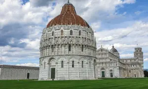 Il Battistero e la Torre Pendente nel centro di Pisa, sotto un cielo nuvoloso.