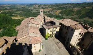 Vista aerea del borgo di Vigoleno, con tetti in cotto e un campanile che domina il paesaggio collinare.