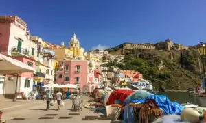 Colorate case a picco sul mare, un porto con reti da pesca e la fortezza in collina: ecco cosa vedere a Procida, un gioiello italiano.